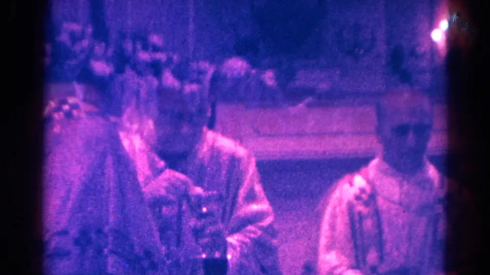 1966 Danville 8mm frame showing three seated people in a dim interior, with one central figure appearing to hold a glass.