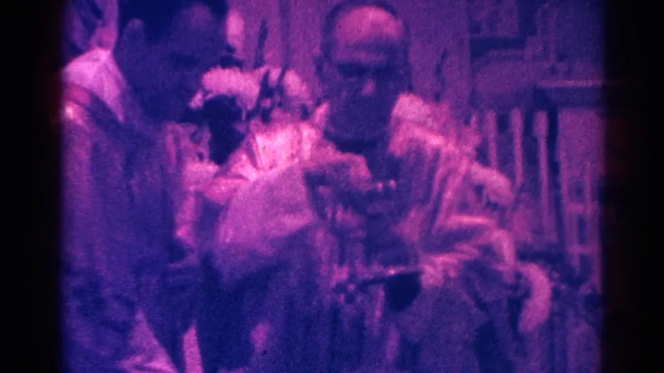 1966 8mm frame from Danville showing clergy gathered closely around the chalice in a Catholic Mass.