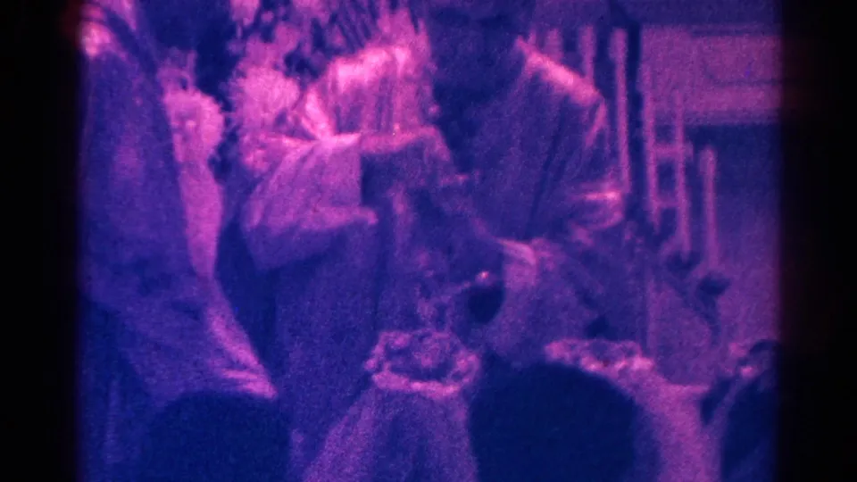 Final 1966 Danville frame showing a priest administering communion near children and pews inside the church.