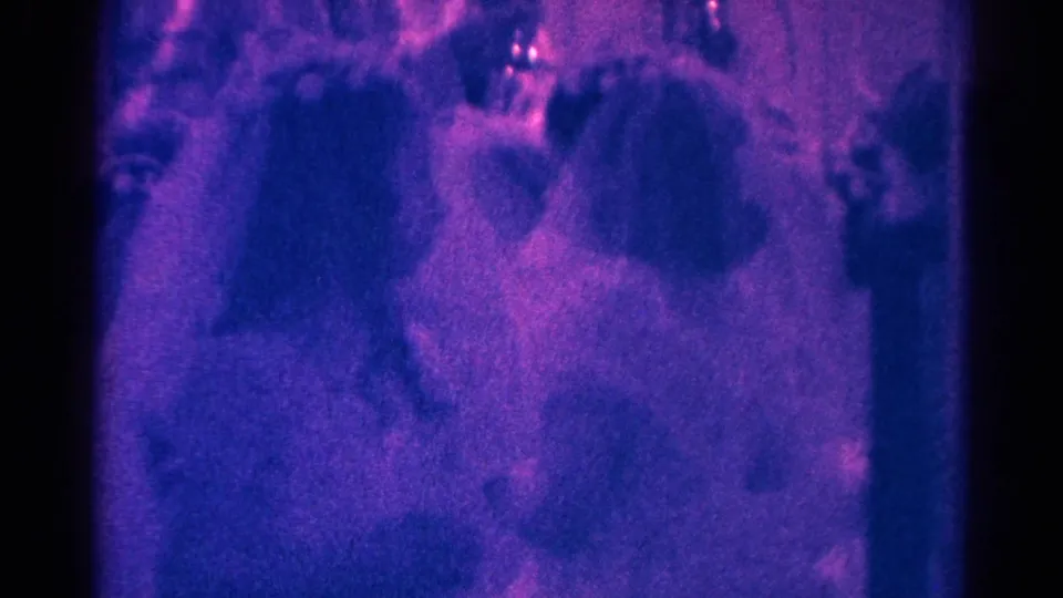 1966 Danville home-movie frame showing girls in light dresses near seated adults during a church ceremony.