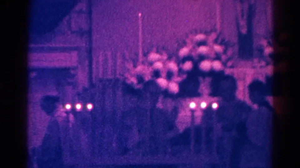 A soft 8mm view of the Danville church ceremony shows foreground candles, altar flowers, and gathered participants in 1966.