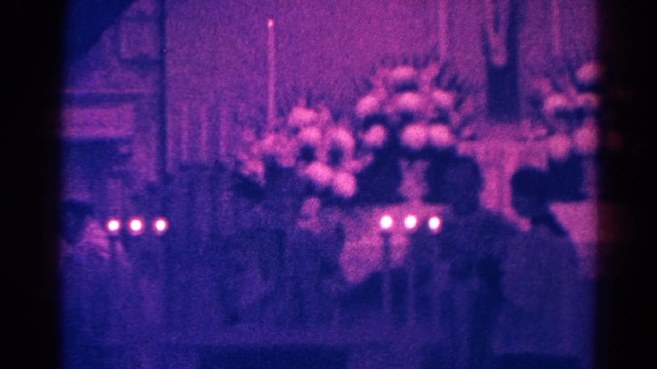 Candlelit church interior with flowers, silhouetted people, and a hanging Jesus display.