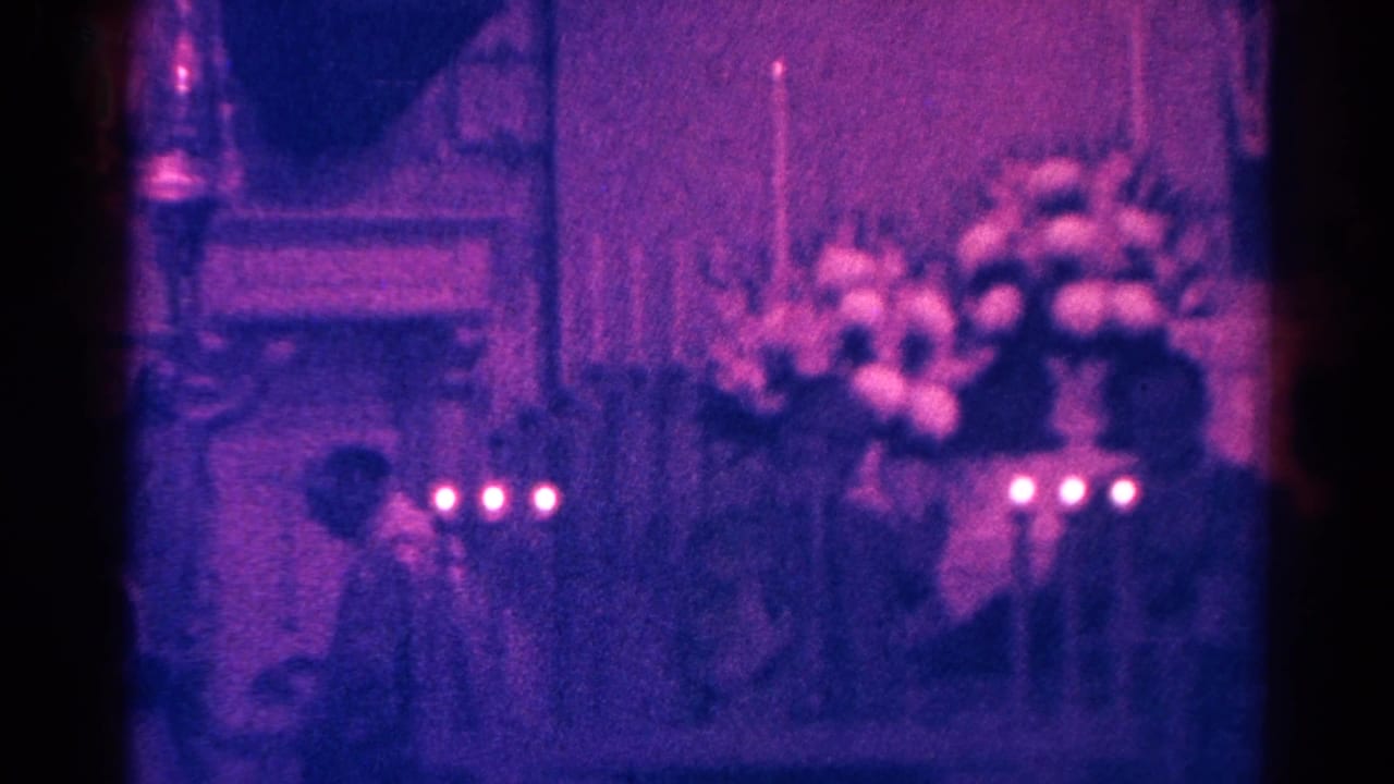 Low-light 1966 home-movie frame from Danville showing candle flames and flowers beneath a religious Jesus display inside a church.