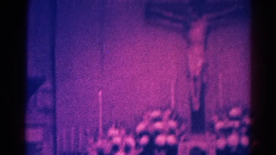 Danville 1966 8mm frame with a crucifix-like Jesus figure centered above flowers and candles in a dark church interior.