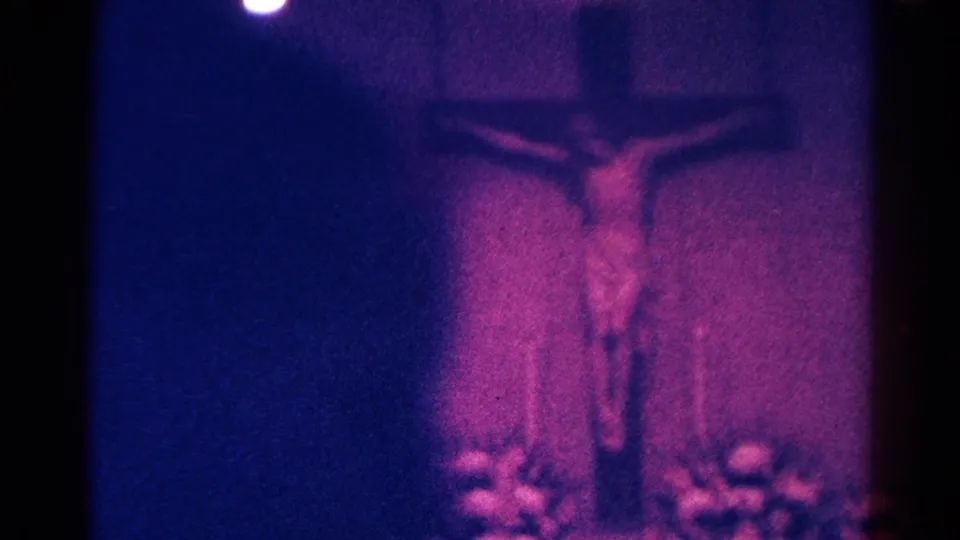 Low-exposure 1966 Danville church frame showing a Jesus display above flowers, partly obscured by dark film edge and color shift.
