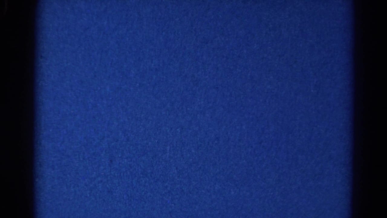 Blue low-light film frame with dark vertical bars and visible grain.