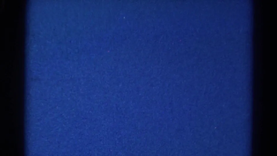 Grainy blue 8mm frame from the Danville 1966 clip, showing exposure banding and frame-edge shadows rather than clear game action.