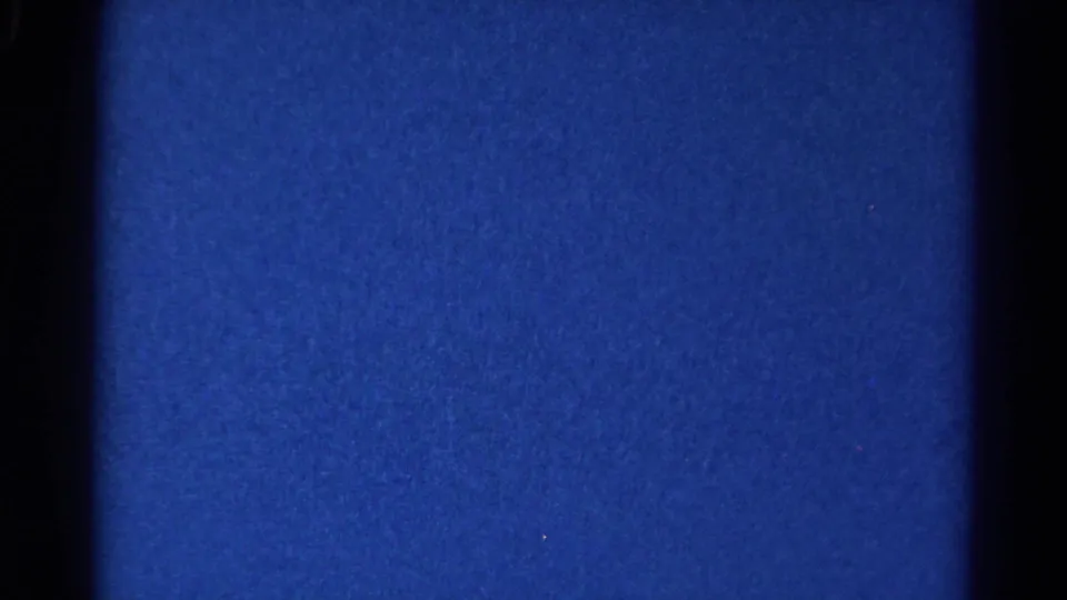 Blue exposed 8mm frame with dark borders, visible grain, and small dust marks, from the 1966 Danville home-movie clip.