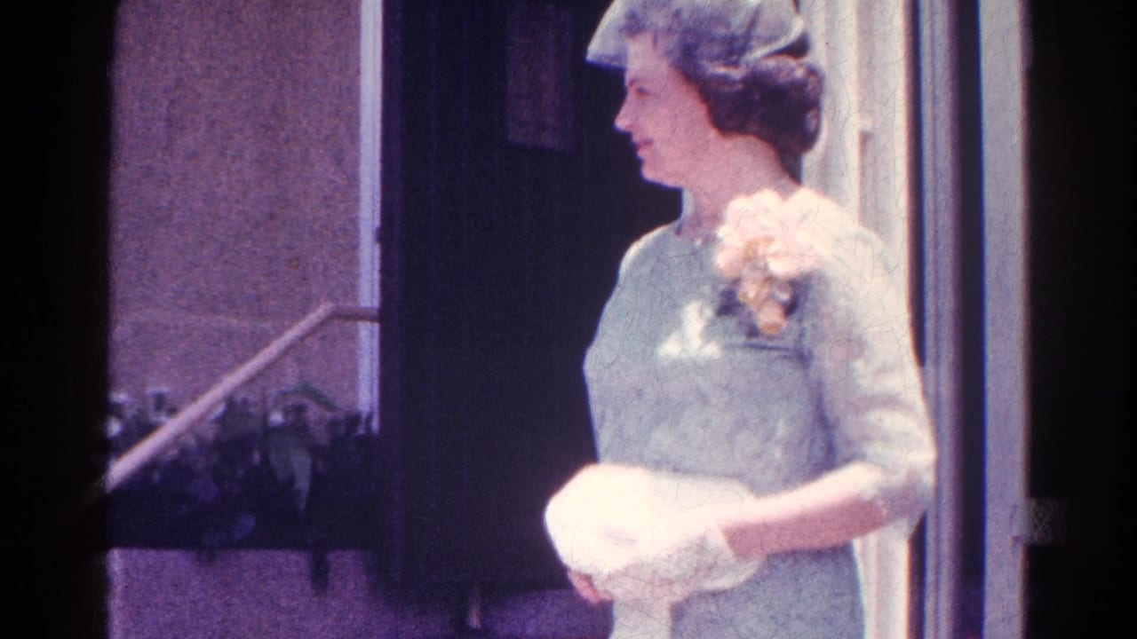 Woman in light blue formal dress and hat stands near an entrance holding a white clutch.