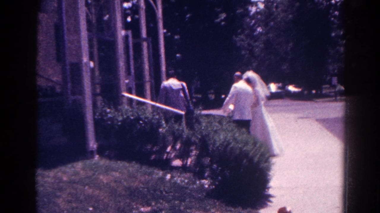 Bride and groom walk along a paved path toward a chapel entrance.