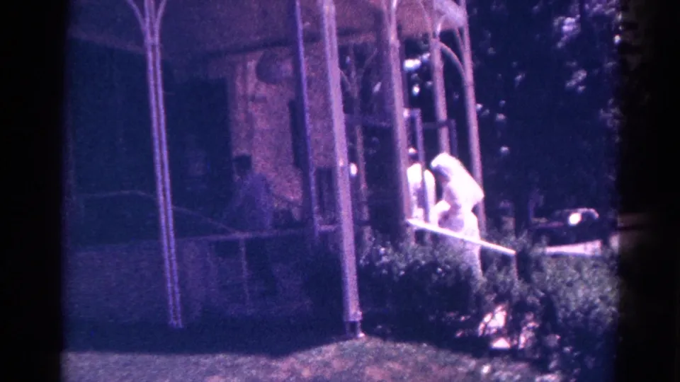 A white-veiled bride is visible at the chapel entrance during the 1966 Danville wedding home movie, with the groom partly obscured.