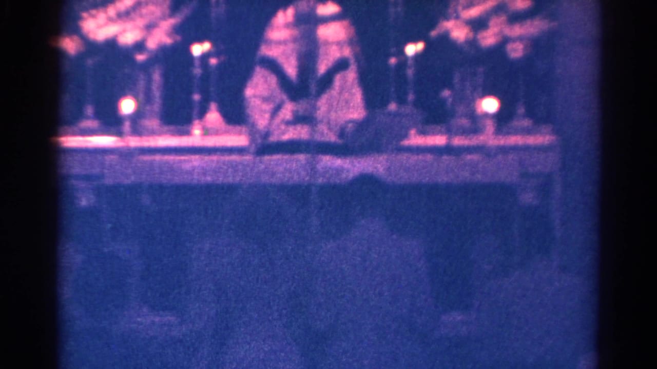 Vested pastor stands at a candlelit church altar with an open book.