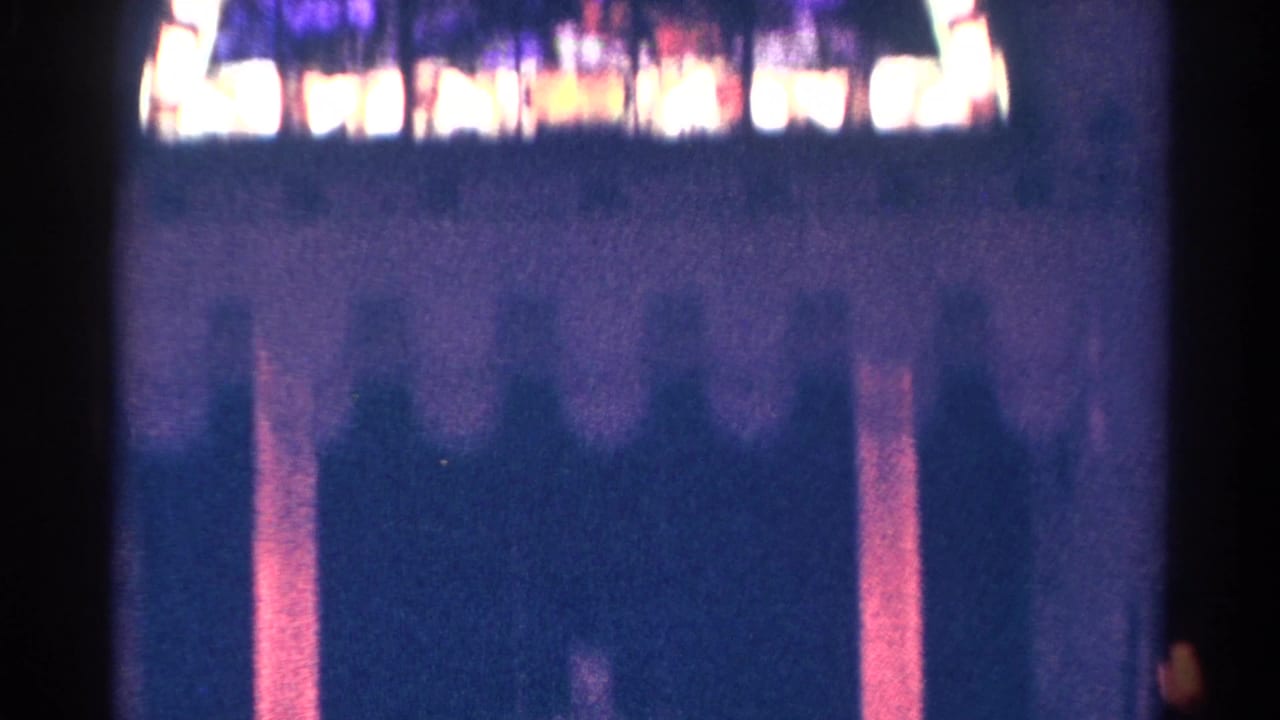 1966 Danville, Illinois 8mm frame with a dim interior wall and a blurred band of stained glass above.