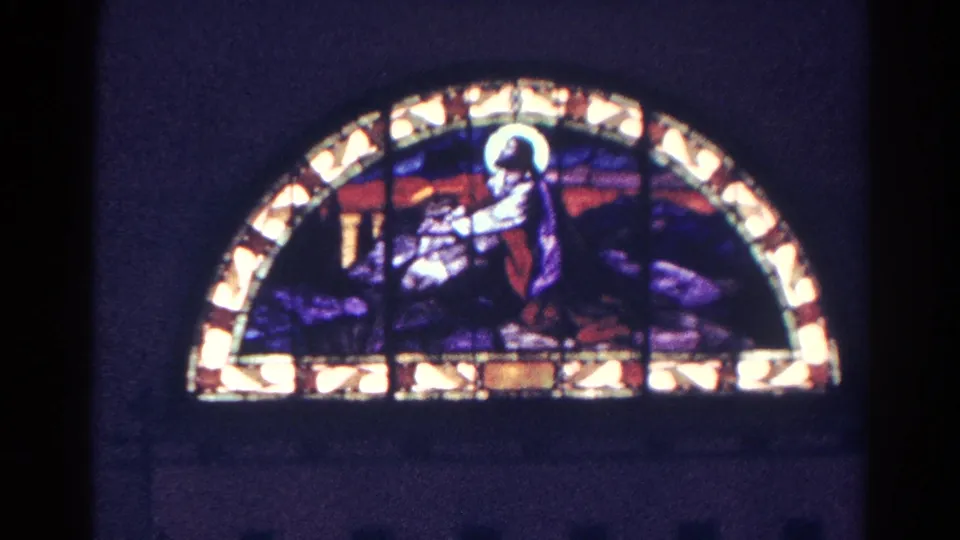 1966 Danville, Illinois 8mm frame showing a semicircular stained glass window with a haloed Christian figure in blue, red, and gold tones.