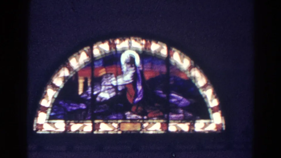 1966 Danville, Illinois 8mm frame holding on a semicircular stained glass window with a haloed Christian figure.