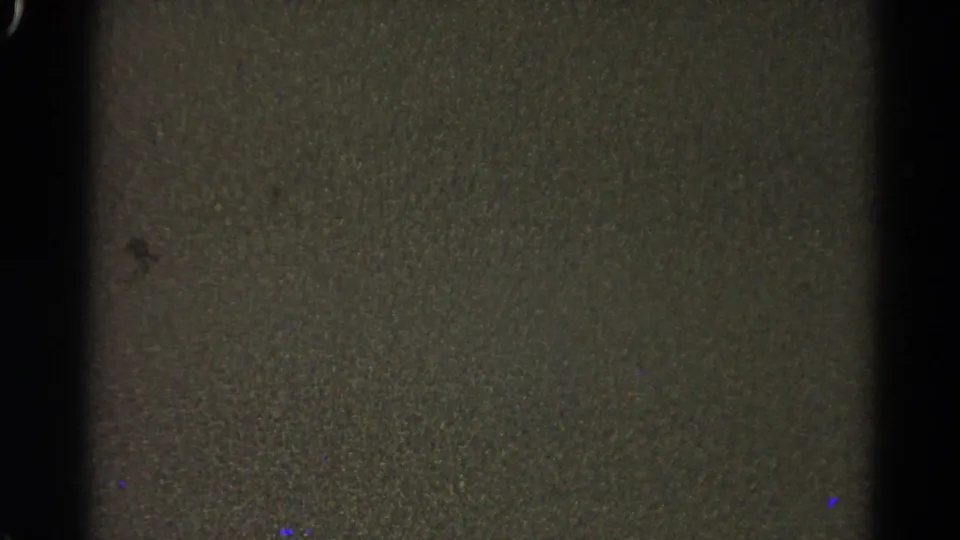 Dark closing 8mm frame with gray-brown grain, vertical frame edges, and no distinct people or objects visible.