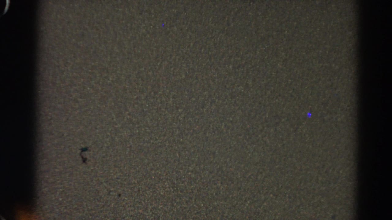Dark grainy film frame with vertical black edges and little visible subject detail.