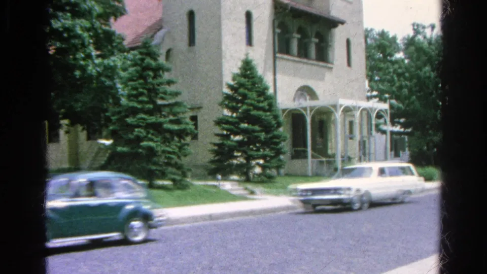 1966 Danville, Illinois frame showing a blue car and white station wagon driving past the church exterior and front lawn.