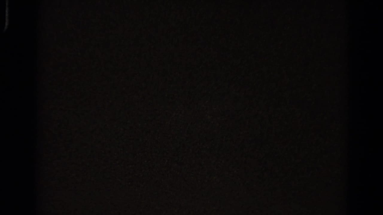 Mostly dark film frame with little visible detail.