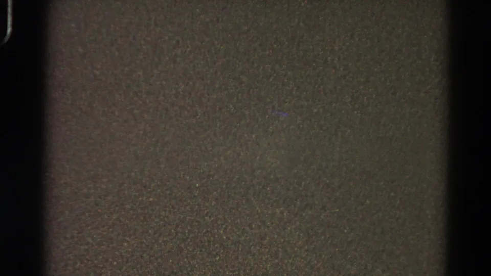 Low-exposure 8mm frame showing grain, muted color, and a vertical dark film-edge band.
