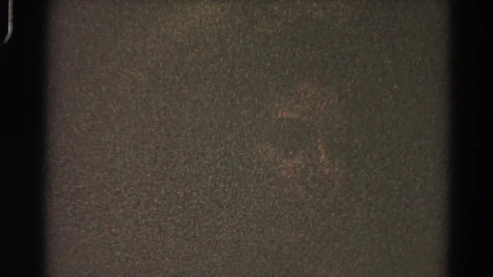 Dark final 8mm frame with visible grain, subdued color noise, and heavy edge shadowing.