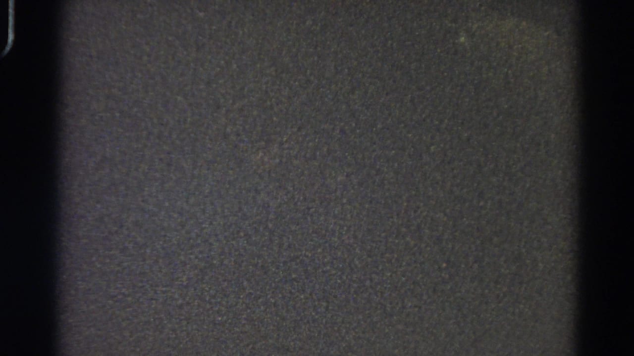 Dark grainy 8mm frame with black gate edges and no discernible subject.