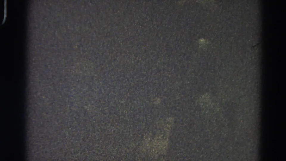 Underexposed 8mm frame from the 1966 Danville reel showing mottled grain, a black vertical gate mark, and no identifiable subject.