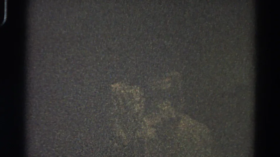 Low-light 1966 Danville 8mm frame showing a vague pale form against dark grain, with scratches and gate-edge artifacts.
