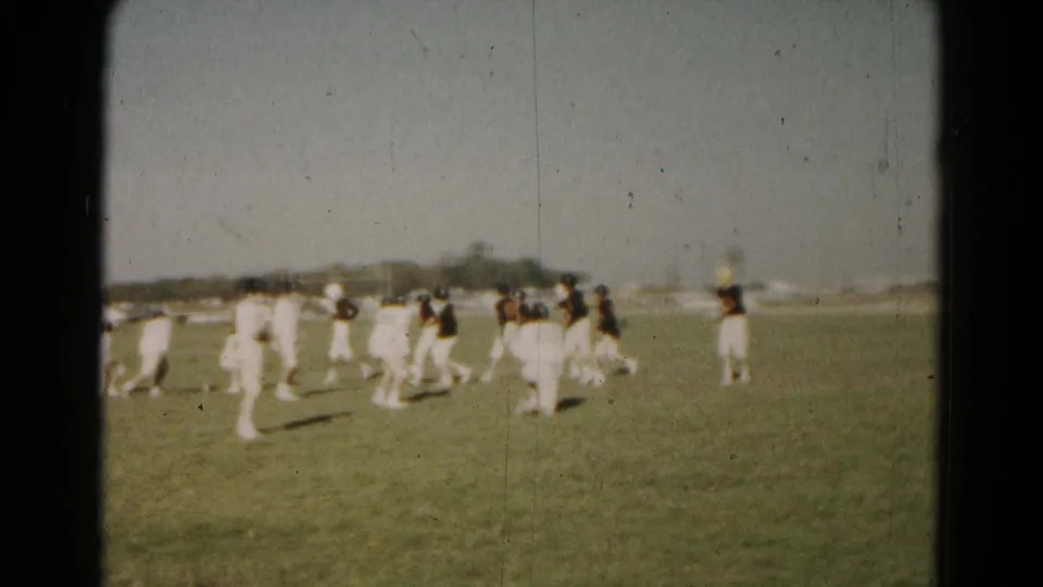 Youth football players move through open-field action in 1966 Hagerstown 8mm footage, with teams in contrasting uniforms.