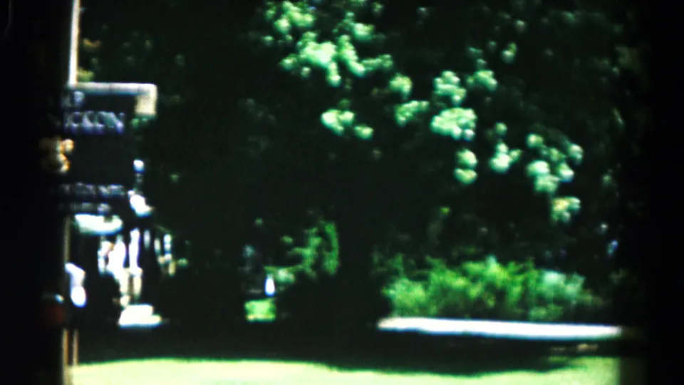 Final 1966 Hagerstown frame with a Camp Kanicron sign partly visible beside trees, bright grass, and a driveway or road edge.