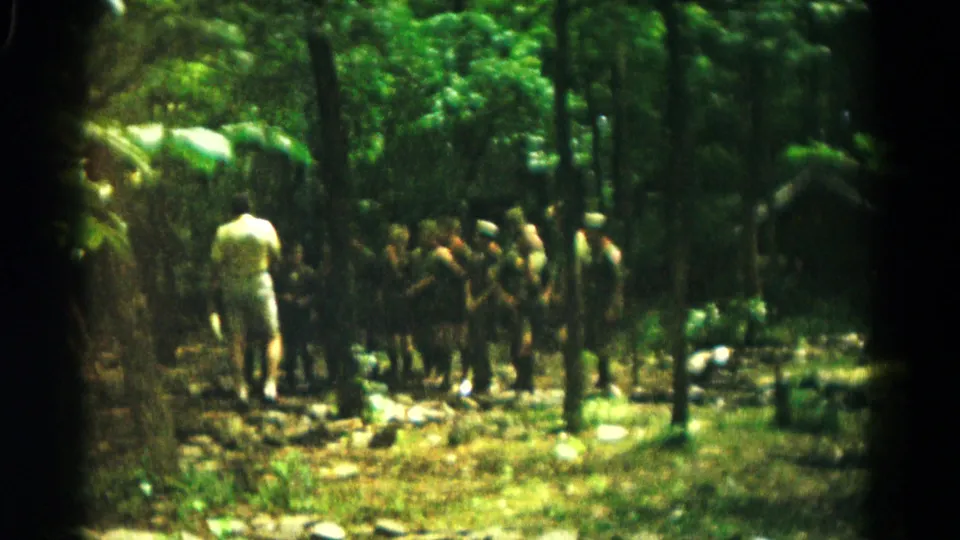 A distant 1966 Hagerstown camp scene with an adult appearing to lead boys in a shaded forest setting.