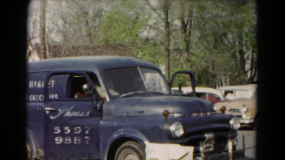 1966 Hagerstown frame showing the front and side of the blue Frank's Market van with an open door and cars behind it.