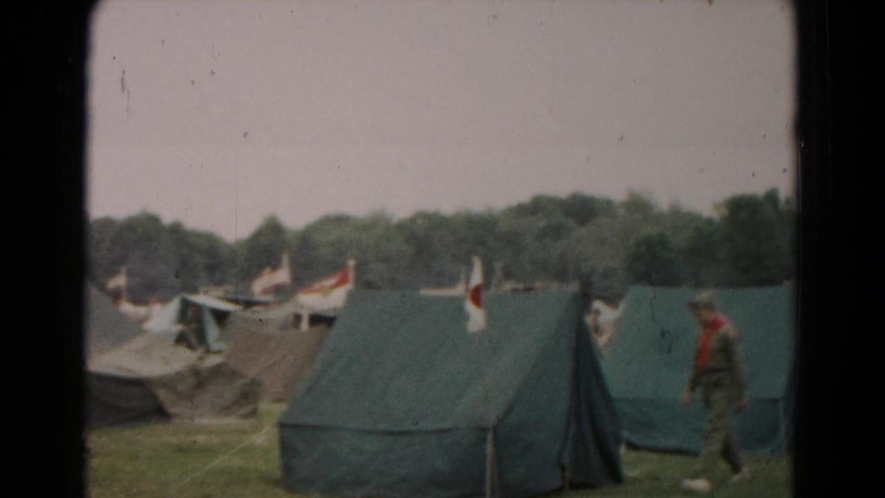 A uniformed scout-style figure walks near green canvas tents in the 1966 Maryland camp footage.