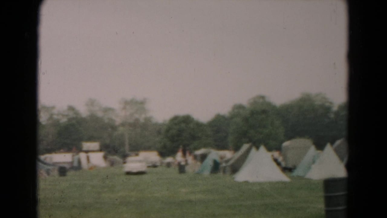 A 1966 Hagerstown tent field seen from a distance, with cars, trees, and small figures between the tents.