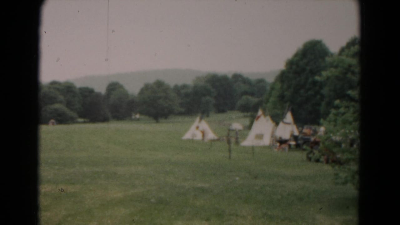 Wide 1966 Hagerstown view of a grassy field, scattered canvas tents, trees, and a distant hill under a pale sky.