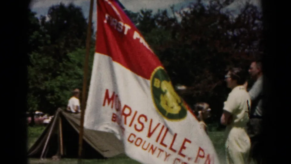 1966 Hagerstown campsite view with a First Presbyterian Church of Morrisville flag, canvas tents, trees, and adults nearby.