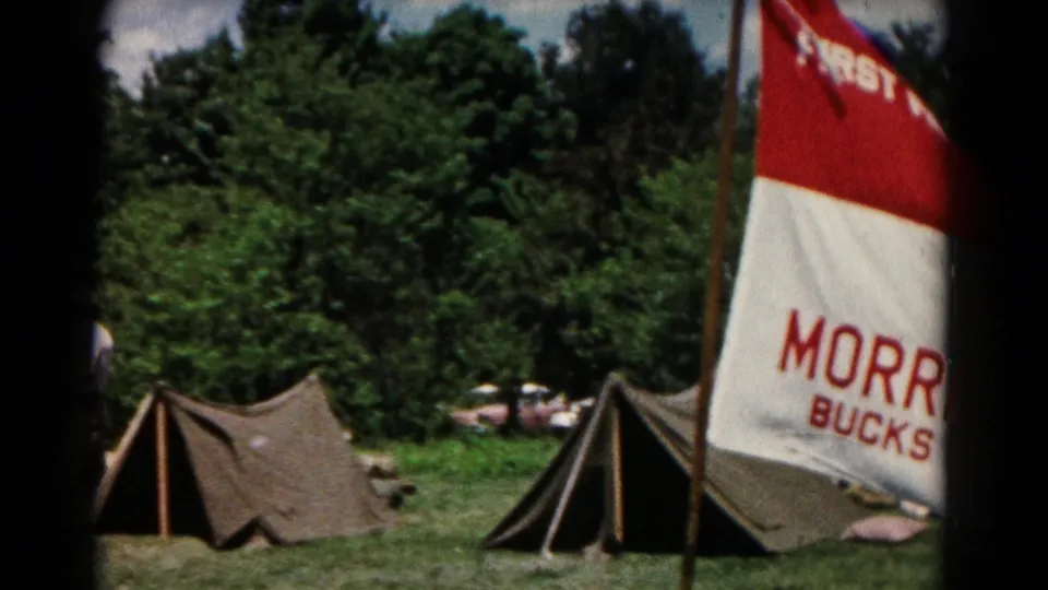 Campsite in Hagerstown, Maryland, with A-frame tents, trees, and a partially visible Morrisville church flag.