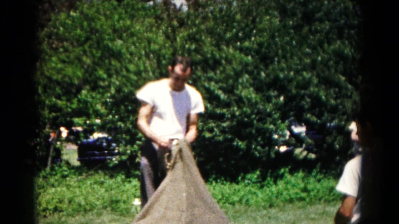 Man looks down while working with the top of a large sack outdoors.