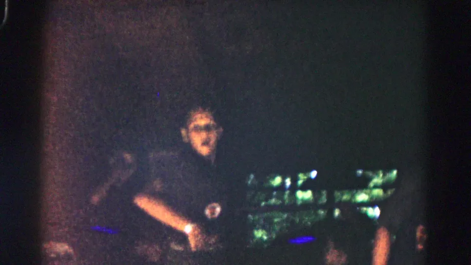 In this 1966 Hagerstown home-movie frame, a person in dark clothing faces the camera while nearby figures remain partly obscured by darkness.