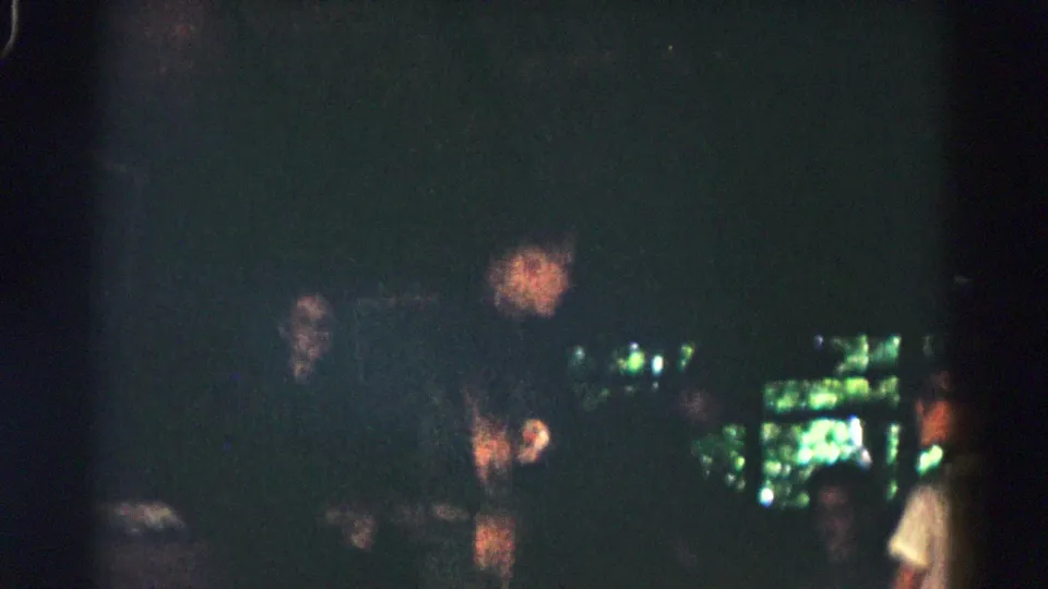 Opening 1966 home-movie frame with shadowed people visible near a bright green outdoor opening, before the camp sign appears clearly.