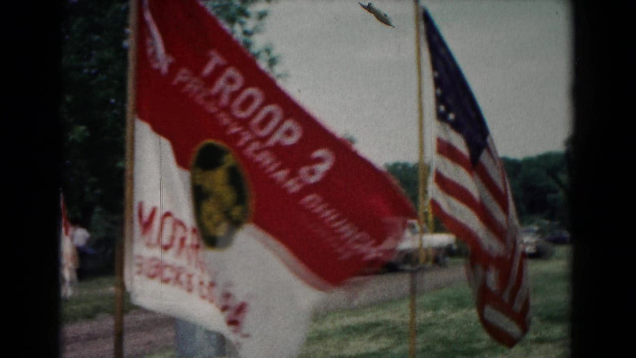 1966 Hagerstown scouting camp view with a red and white Troop 3 flag and an American flag near parked cars.