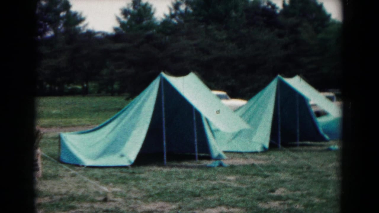 1966 Hagerstown, Maryland campsite view with green canvas tents, pine trees, and a partly visible parked car behind the tent row.