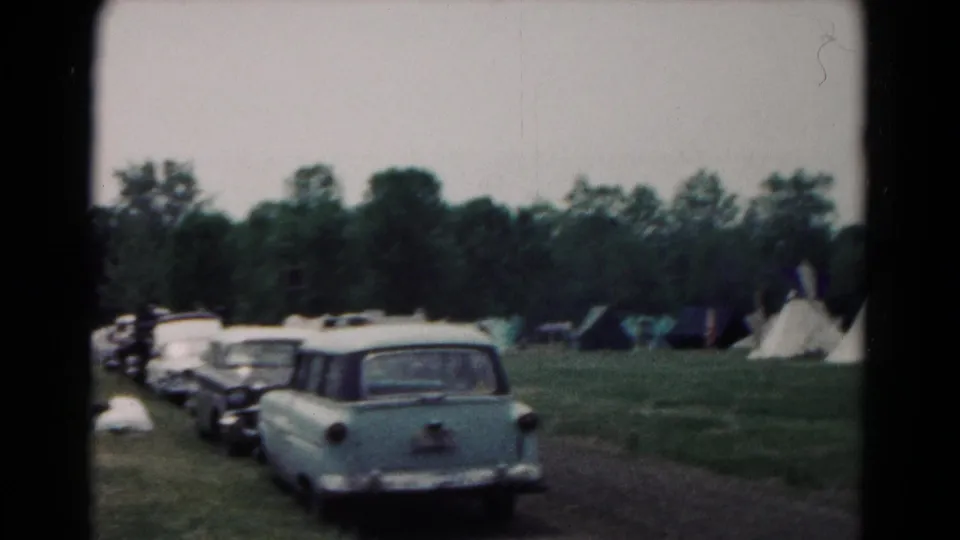 1966 Hagerstown frame showing a light station wagon, nearby cars, blue tents, white teepee-style tents, and a grassy field.