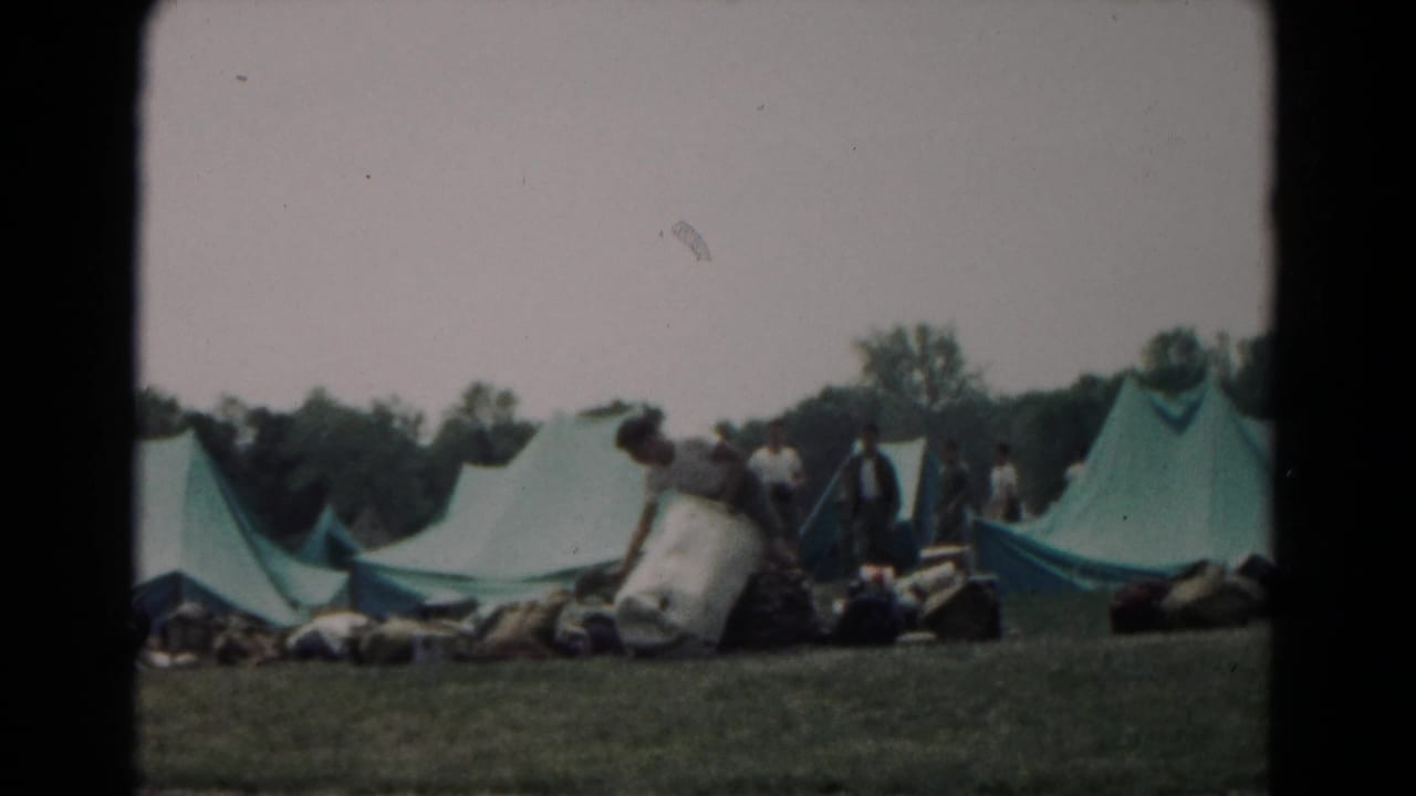 A 1966 Hagerstown campsite with large green tents, bedrolls or supplies, and several people gathered nearby.