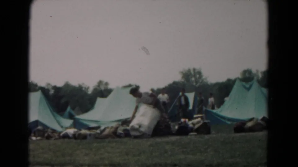 A 1966 Hagerstown campsite with large green tents, bedrolls or supplies, and several people gathered nearby.