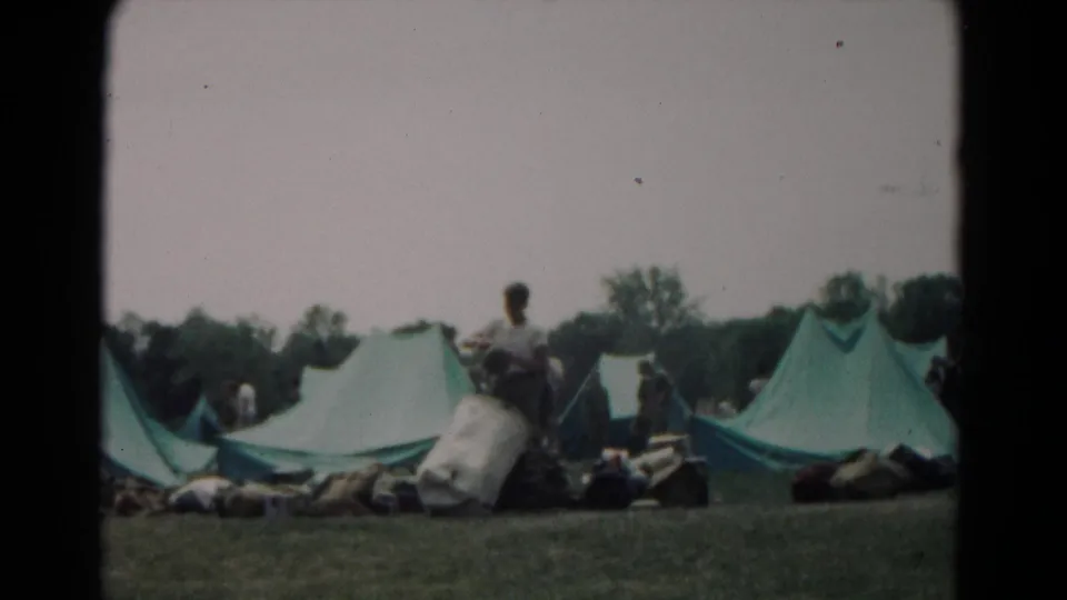 At a 1966 Hagerstown campsite, a young man appears to handle or unpack supplies beside green canvas tents.