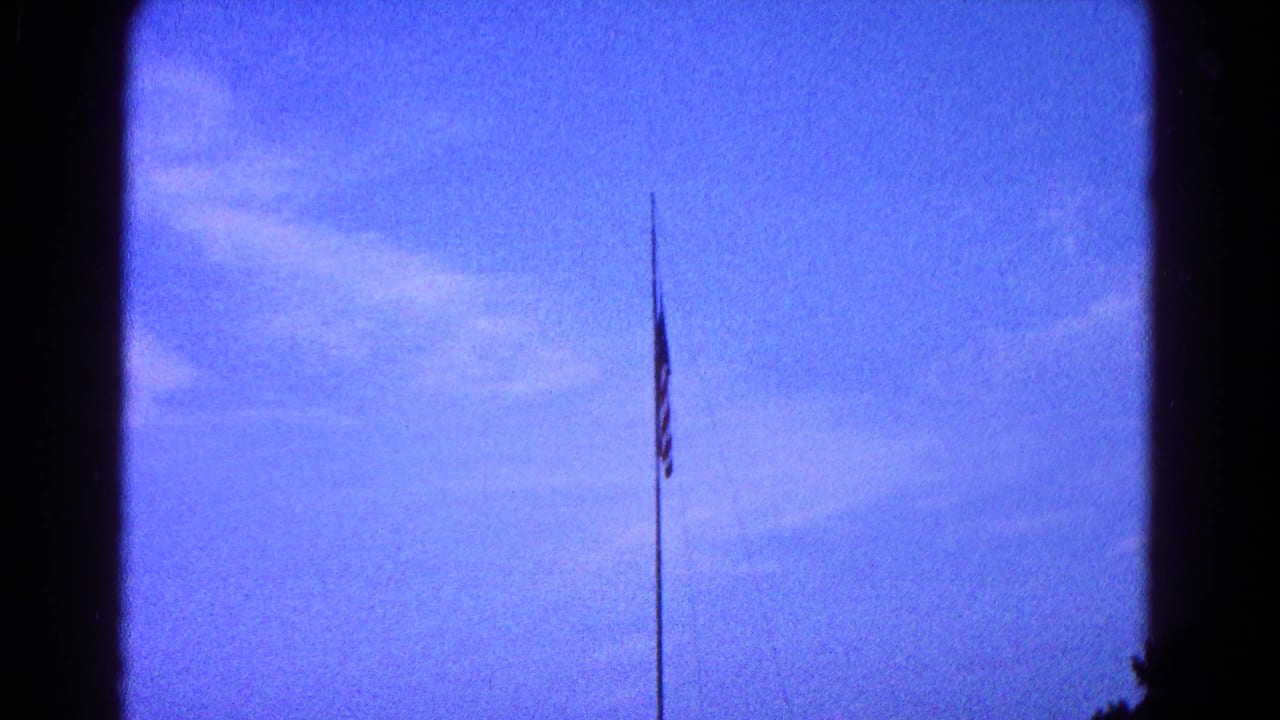 American flag partway down a tall pole against blue sky and wispy clouds.