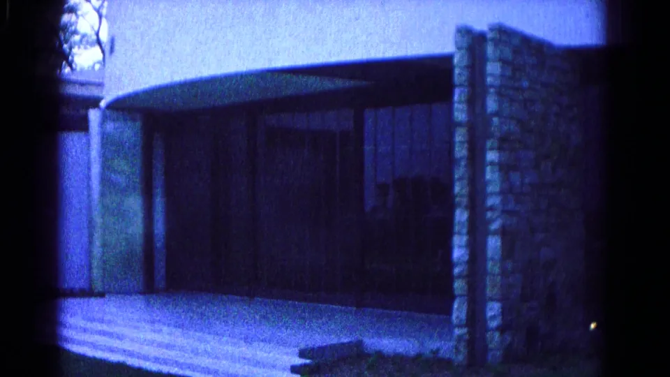 1966 Hagerstown home-movie frame showing a modernist exterior with curved roofline, stonework, glass doors, and broad steps.