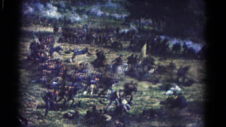 A wider filmed view shows the battle painting with dense infantry, cavalry movement, fallen figures, trees, and muted 8mm color.