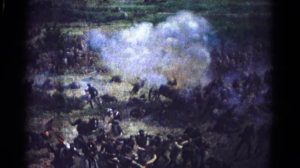 Civil War reenactment footage shows dense cannon smoke spreading across a Hagerstown field as figures move nearby.